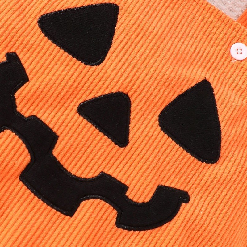 Détail du visage de citrouille noir appliqué sur la salopette en velours côtelé orange